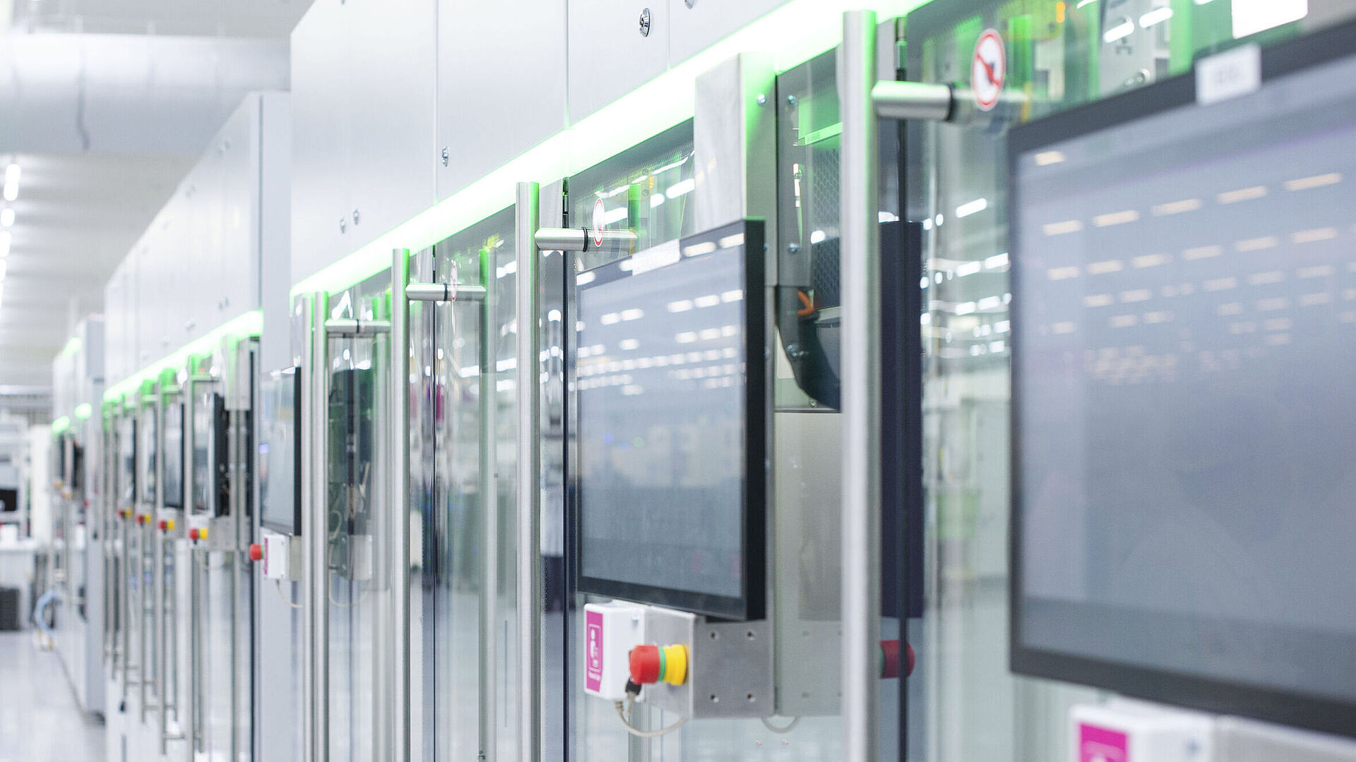 Automated production line with modern machines and touchscreens in a bright manufacturing hall.