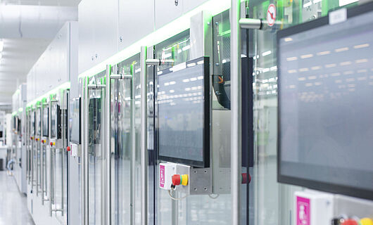 Automated production line with modern machines and touchscreens in a bright manufacturing hall.