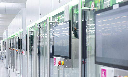 Automated production line with modern machines and touchscreens in a bright manufacturing hall.