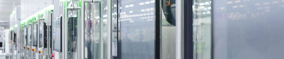 Automated production line with modern machines and touchscreens in a bright manufacturing hall.