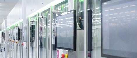 Automated production line with modern machines and touchscreens in a bright manufacturing hall.