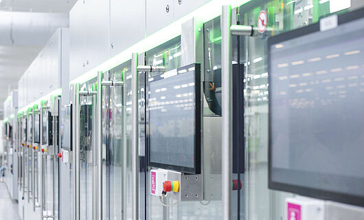 Automated production line with modern machines and touchscreens in a bright manufacturing hall.