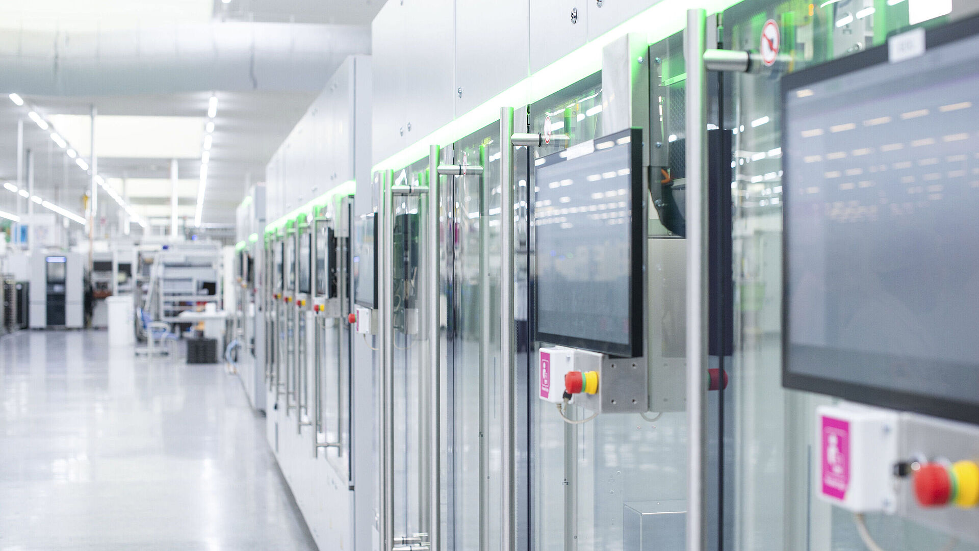 Automated production line with modern machines and touchscreens in a bright manufacturing hall.