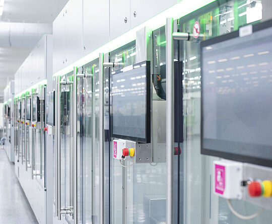 Automated production line with modern machines and touchscreens in a bright manufacturing hall.