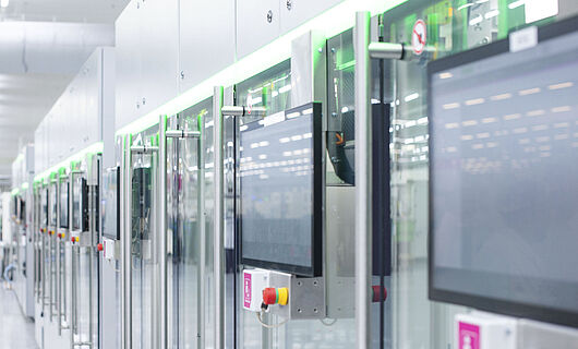 Automated production line with modern machines and touchscreens in a bright manufacturing hall.