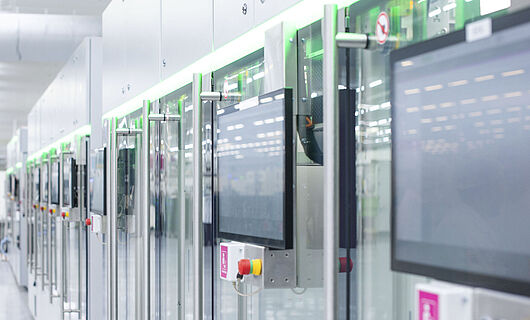 Automated production line with modern machines and touchscreens in a bright manufacturing hall.