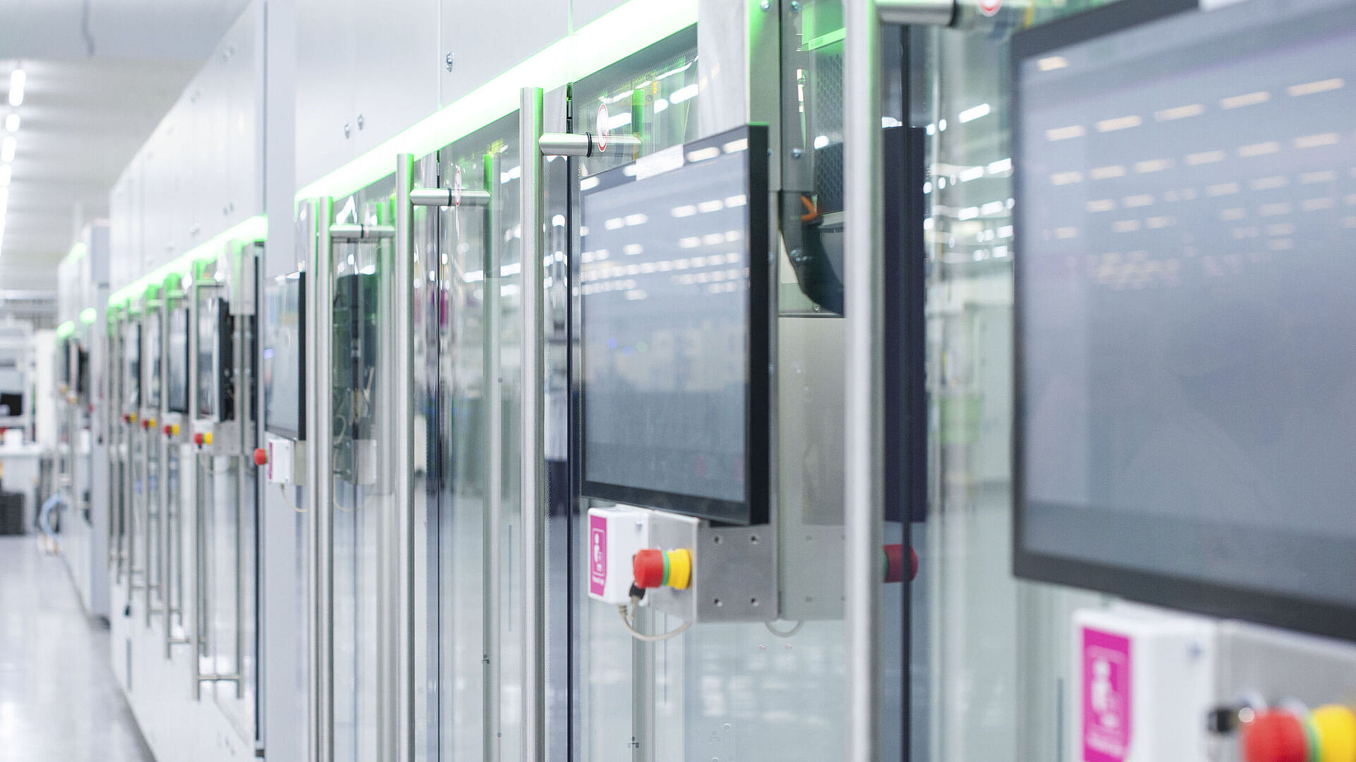 Automatisierte Fertigungslinie mit modernen Maschinen und Touchscreens in einer hellen Produktionshalle.