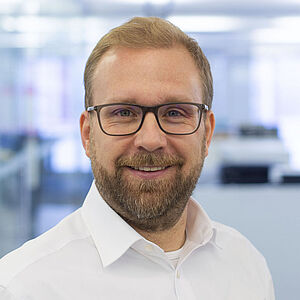 Smiling man in a white shirt. In a well-lit office.