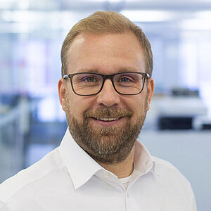 Smiling man in a white shirt. In a well-lit office.