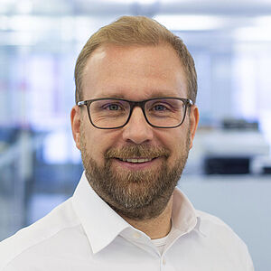 Smiling man in a white shirt. In a well-lit office.