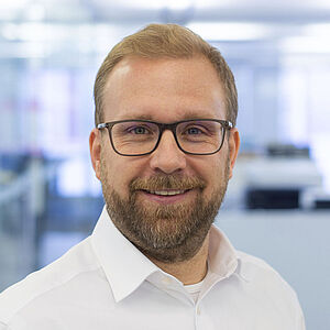 Smiling man in a white shirt. In a well-lit office.