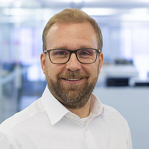 Smiling man in a white shirt. In a well-lit office.