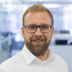 Smiling man in a white shirt. In a well-lit office.