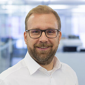 Smiling man in a white shirt. In a well-lit office.