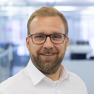 Smiling man in a white shirt. In a well-lit office.