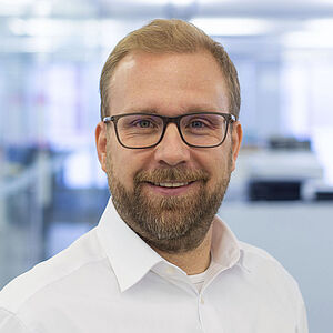 Smiling man in a white shirt. In a well-lit office.