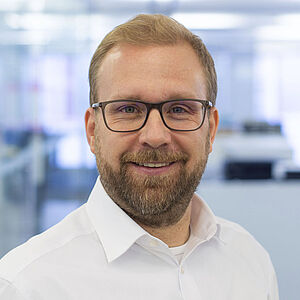 Smiling man in a white shirt. In a well-lit office.