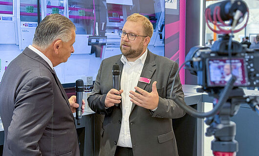 Zwei Männer in einem Interview vor laufender Kamera