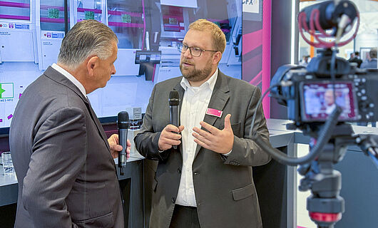 Zwei Männer in einem Interview vor laufender Kamera