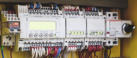 Bright switch devices are wall-mounted and connected from above and below with numerous colorful cables.