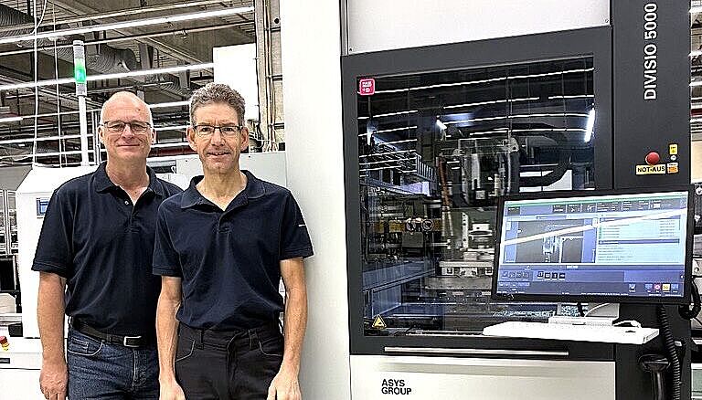 Two men standing next to a machine.