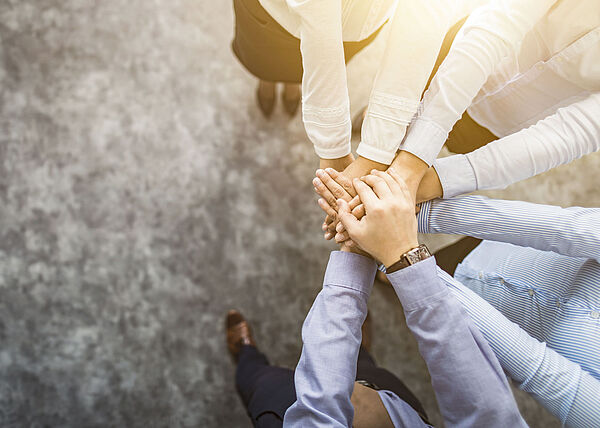 Four people place their hands together in the center.