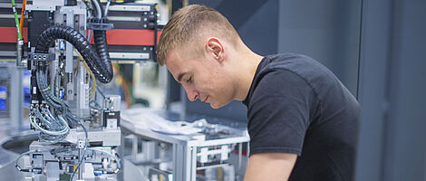 Ein junger Mann arbeitet konzentriert an einer Maschine.