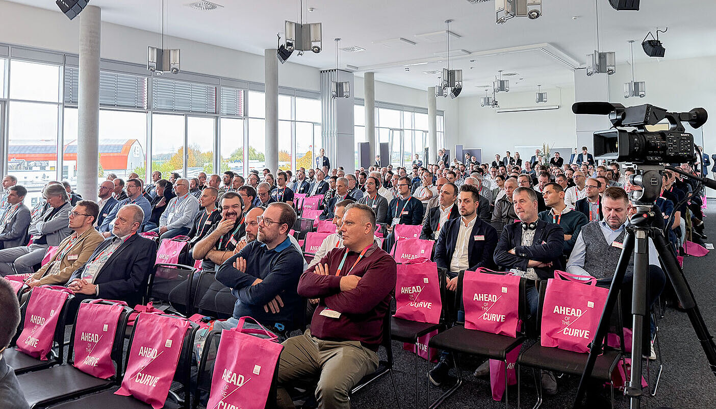 Several people are sitting in a row in a meeting room.