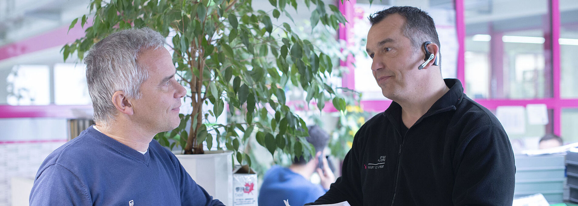 Two men are standing at a counter and looking at each other.