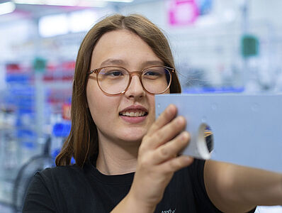Young woman taking a measurement in a production hall.