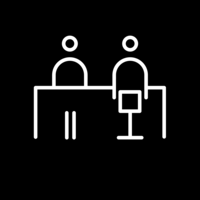 White pictogram of two people sitting opposite each other at a table on black background.