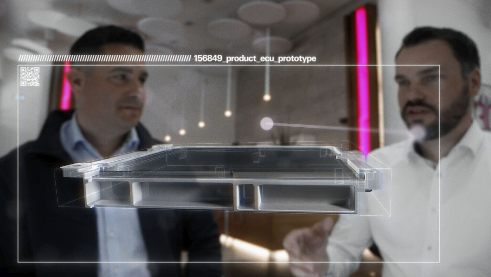 Two men standing side by side, with a hologram of a prototype in front of them.