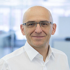 A smiling man is wearing a white shirt.