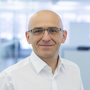 A smiling man is wearing a white shirt.