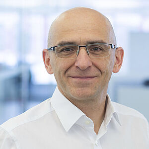 A smiling man is wearing a white shirt.