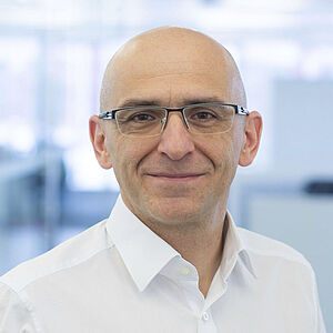 A smiling man is wearing a white shirt.