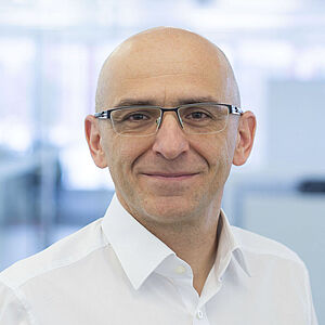 A smiling man is wearing a white shirt.