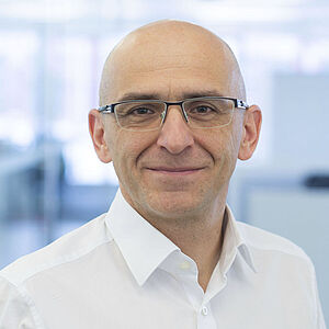 A smiling man is wearing a white shirt.