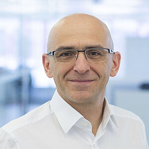 A smiling man is wearing a white shirt.