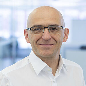 A smiling man is wearing a white shirt.