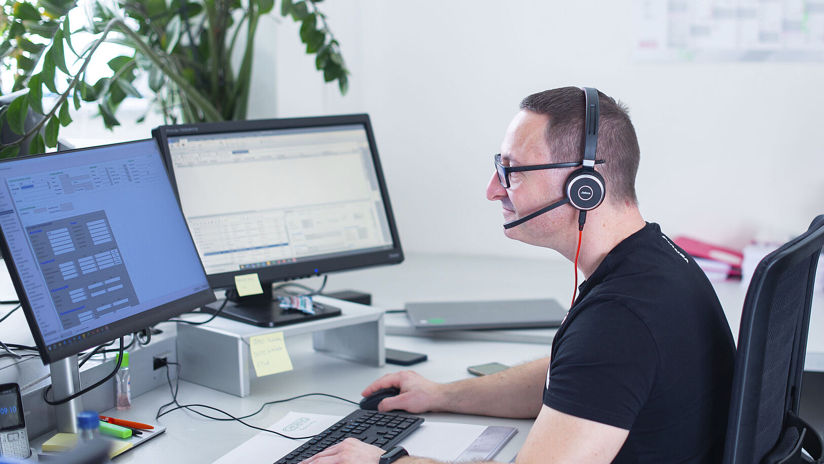 Man sitting at a PC in an office wearing a headset