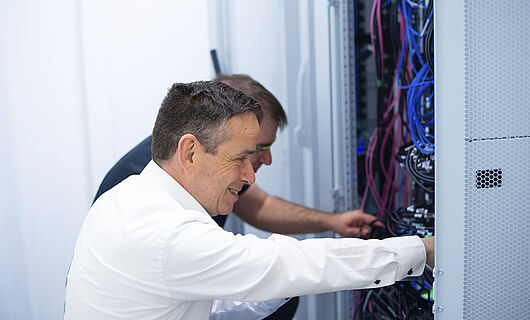 Two men together at an open switch cabinet.