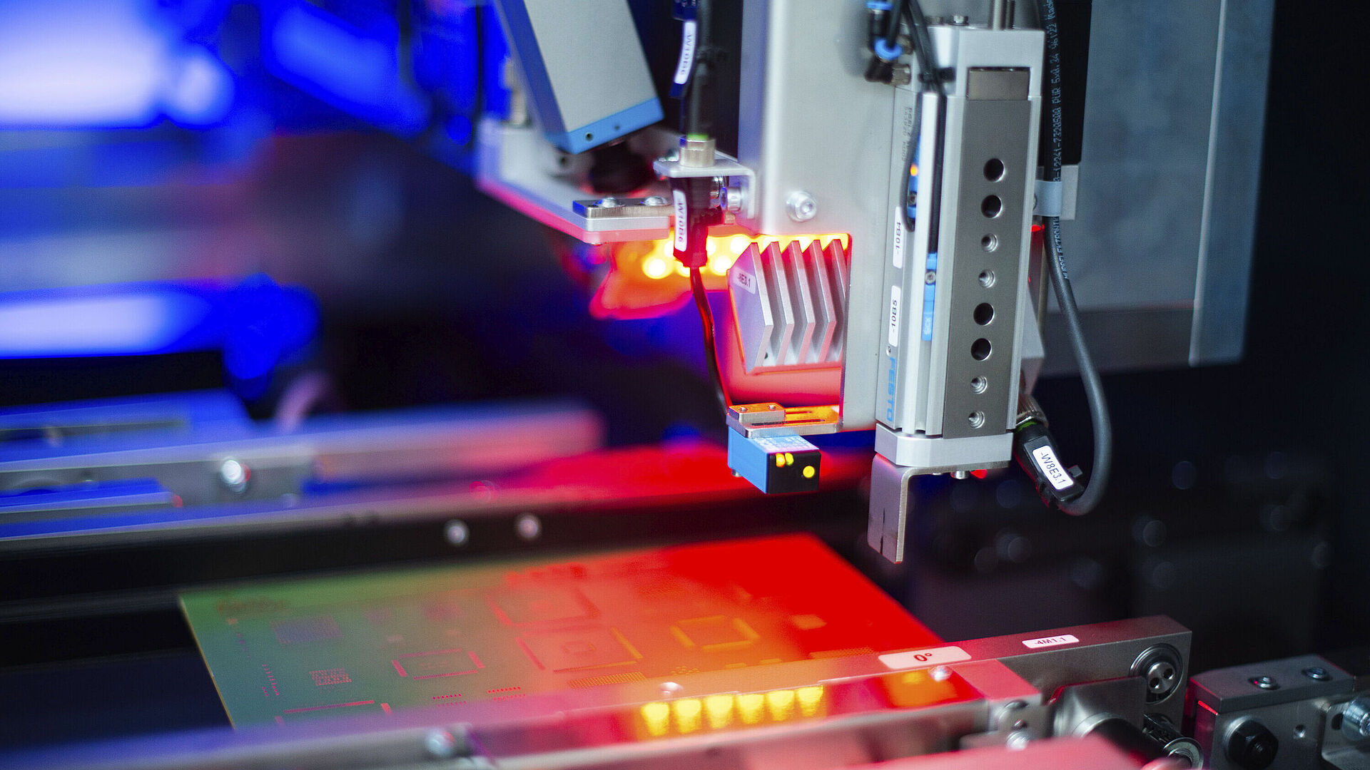 Innenansicht einer Laser Maschine, rotes Licht scheint auf eine eingelegte Leiterplatte.